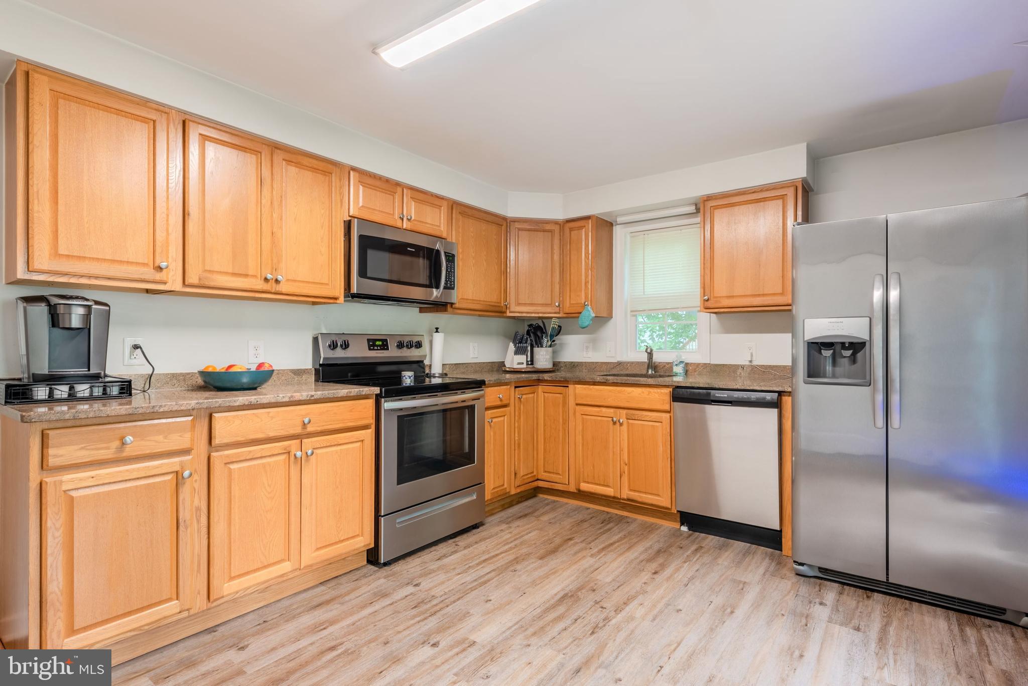 668 Running Fox Road Lusby, MD 20657 - Photo 3 of 12 a kitchen with granite countertop wooden floors stainless steel appliances a sink and a window