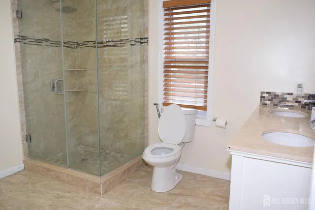a bathroom with a granite countertop toilet a sink and shower