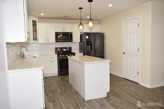 a kitchen with a refrigerator a stove top oven a sink and dishwasher with wooden floor