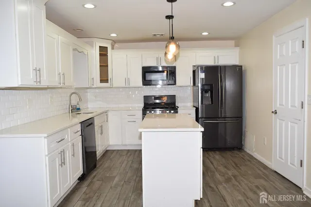 a kitchen with a refrigerator a sink and wooden floor