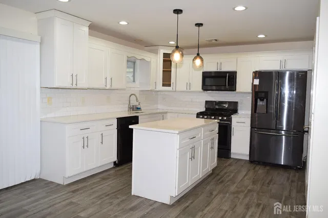 a kitchen with stainless steel appliances granite countertop a refrigerator a stove a sink dishwasher and a oven with wooden floor