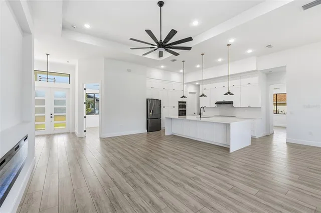 a view of an empty room and kitchen with wooden floor