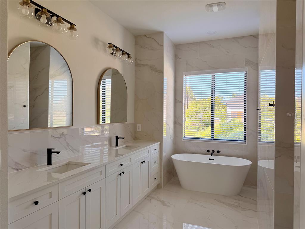 210 Tournament Road Rotonda West, FL 33947 - Photo 18 of 59 a bathroom with a double vanity sink a mirror and a bathtub
