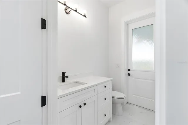 a bathroom with a granite countertop toilet a sink and shower