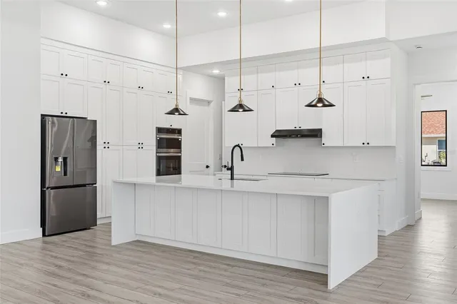 a kitchen with stainless steel appliances kitchen island a refrigerator and a sink