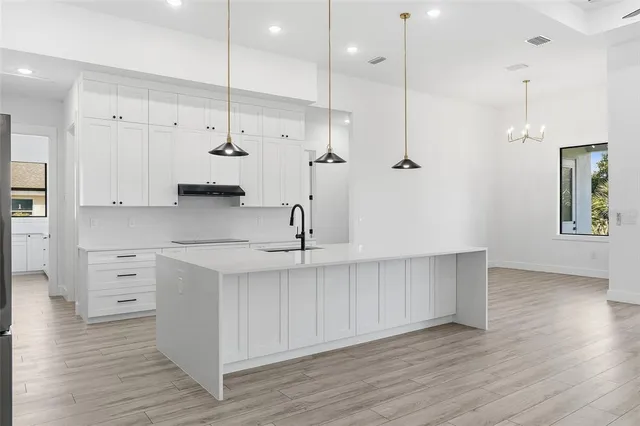 a kitchen with white cabinets and wooden floor