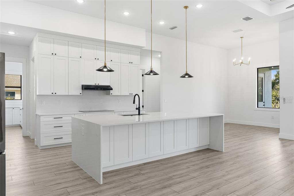 210 Tournament Road Rotonda West, FL 33947 - Photo 10 of 59 a kitchen with white cabinets and wooden floor