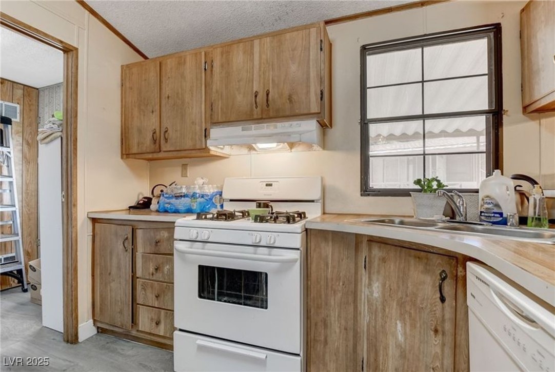 5576 Aldama Road Las Vegas, NV 89122 - Photo 12 of 23 Kitchen featuring white appliances, light countertops, a textured ceiling, under cabinet range hood, and crown molding