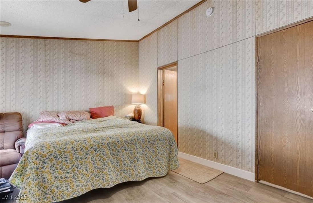 5576 Aldama Road Las Vegas, NV 89122 - Photo 17 of 23 Bedroom with ornamental molding, wood finished floors, ceiling fan, a textured ceiling, and wallpapered walls