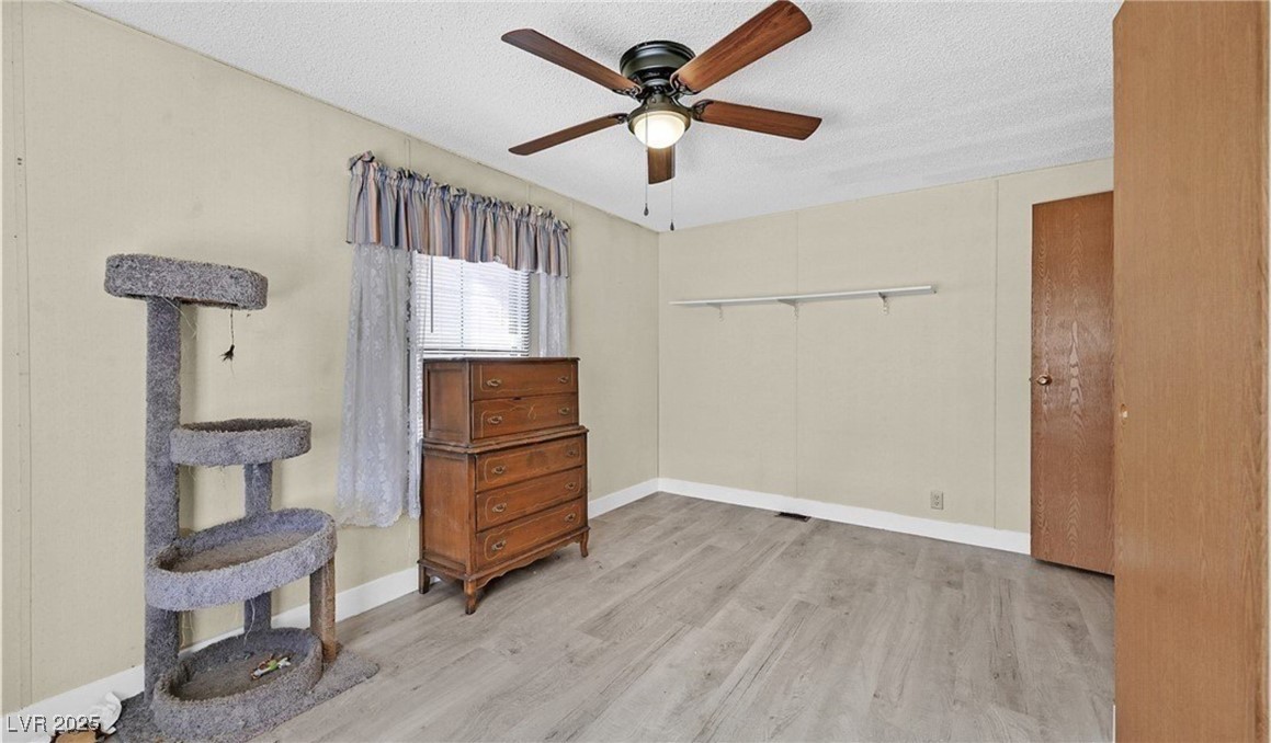 5576 Aldama Road Las Vegas, NV 89122 - Photo 18 of 23 Bedroom with a textured ceiling, a ceiling fan, and light wood-style flooring