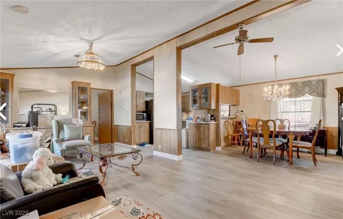 5576 Aldama Road Las Vegas, NV 89122 - Photo 5 of 23 Living area with a chandelier, vaulted ceiling, wainscoting, a ceiling fan, and light wood-style flooring
