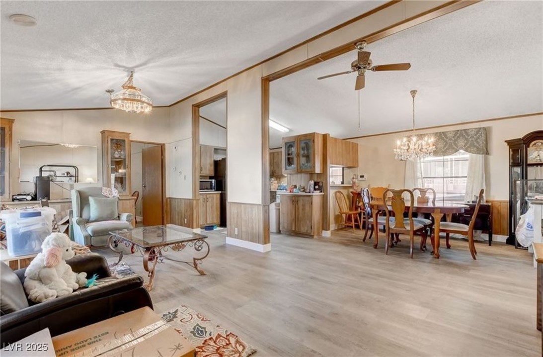 5576 Aldama Road Las Vegas, NV 89122 - Photo 6 of 23 Living area featuring a chandelier, lofted ceiling, wainscoting, ceiling fan, and a textured ceiling