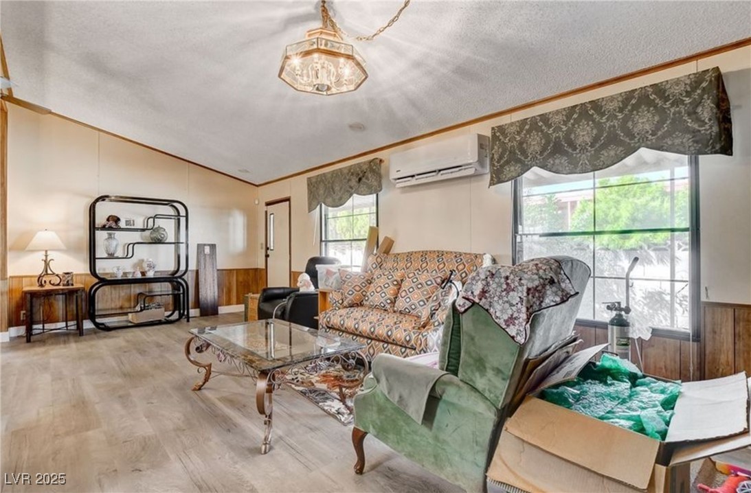 5576 Aldama Road Las Vegas, NV 89122 - Photo 7 of 23 Living area with wainscoting, wooden walls, lofted ceiling, a textured ceiling, and wood finished floors