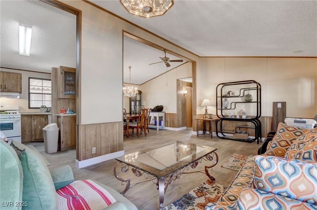 5576 Aldama Road Las Vegas, NV 89122 - Photo 8 of 23 Living area featuring a chandelier, a wainscoted wall, crown molding, wood walls, and light wood finished floors