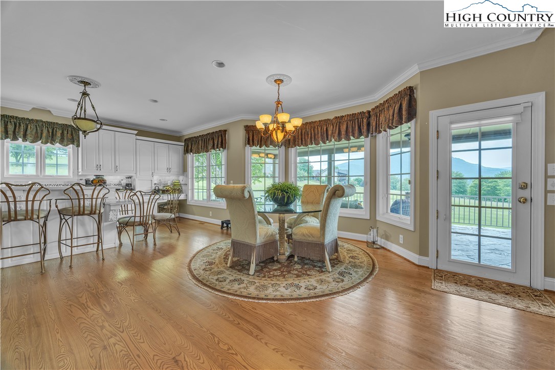 891 Olde Charter Circle Jefferson, NC 28640 - Photo 14 of 49 a dining room with wooden floor a chandelier a glass table and chairs