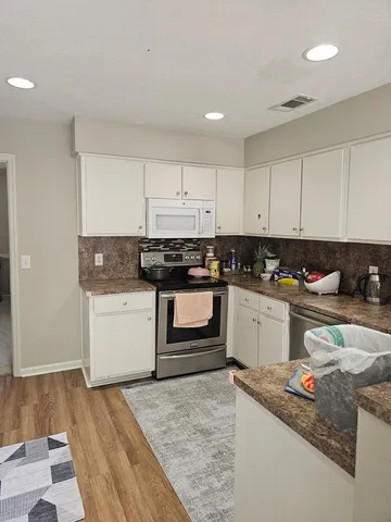 a kitchen with granite countertop white cabinets and white appliances