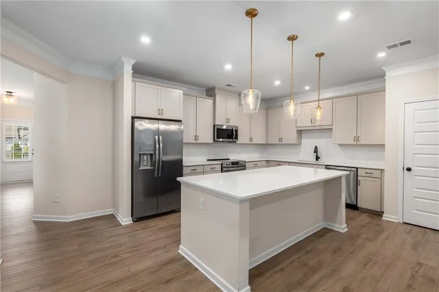 a kitchen with kitchen island a sink stainless steel appliances and wooden floor