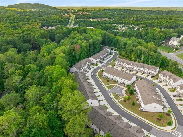 an aerial view of residential houses with outdoor space and trees