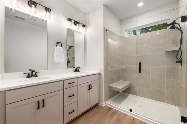 a bathroom with a double vanity sink toilet mirror and shower