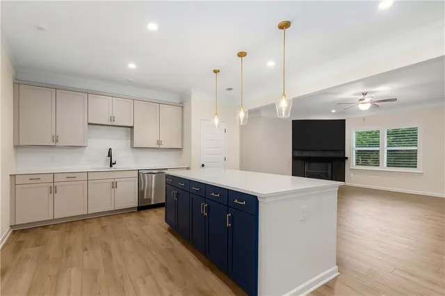 a large kitchen with kitchen island a sink dishwasher a stove a refrigerator and white cabinets with wooden floor