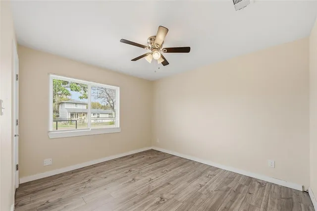 an empty room with wooden floor and ceiling fan