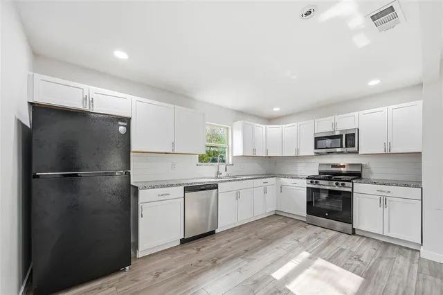 a kitchen with a sink a refrigerator and white cabinets