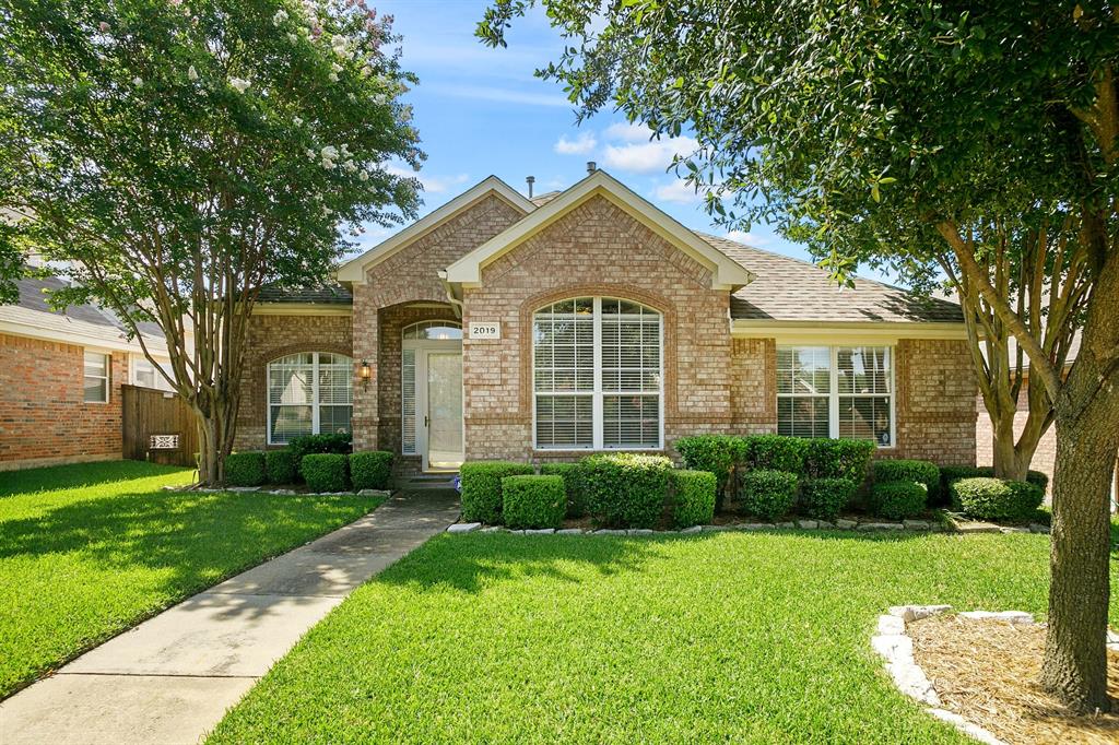 a view of a house next to a yard with plants and trees