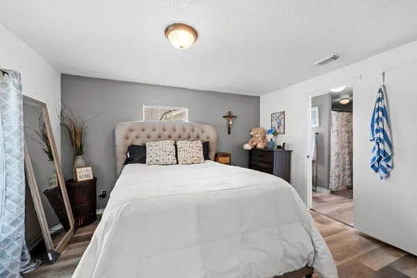 a spacious bedroom with a bed and a flat tv screen on the dresser