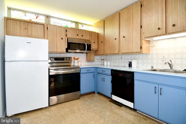 a kitchen with stainless steel appliances a sink dishwasher stove and cabinets with wooden floor