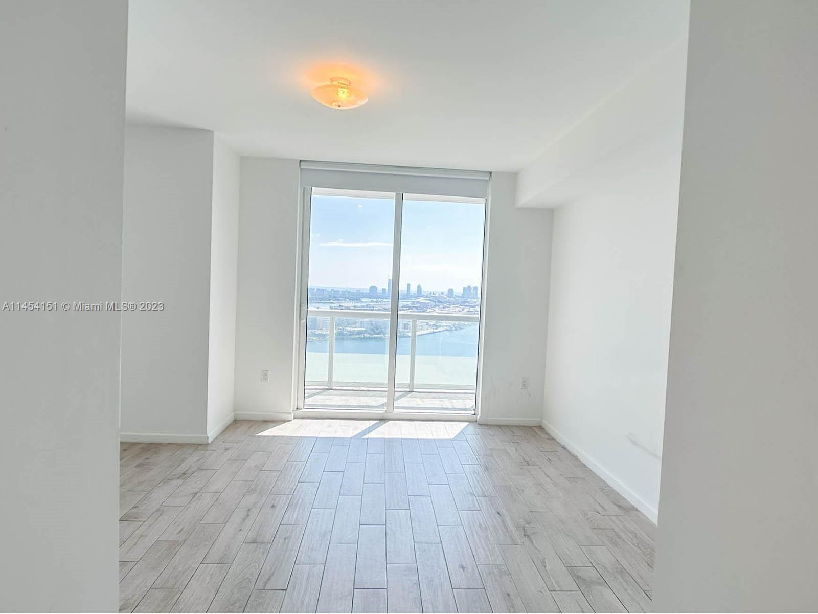 50 Biscayne Boulevard, Unit 3104 Miami, FL 33132 - Photo 19 of 52 an empty room with wooden floor and windows