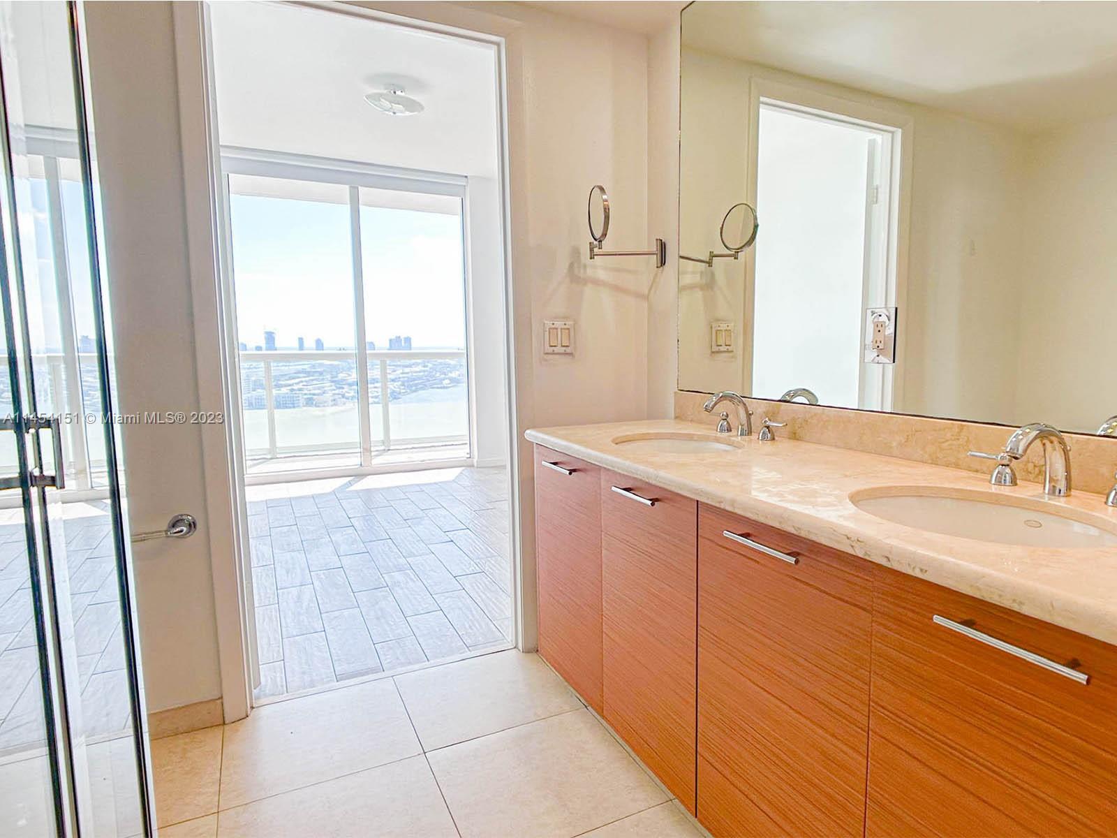 50 Biscayne Boulevard, Unit 3104 Miami, FL 33132 - Photo 29 of 52 a bathroom with a granite countertop sink a mirror and a shower
