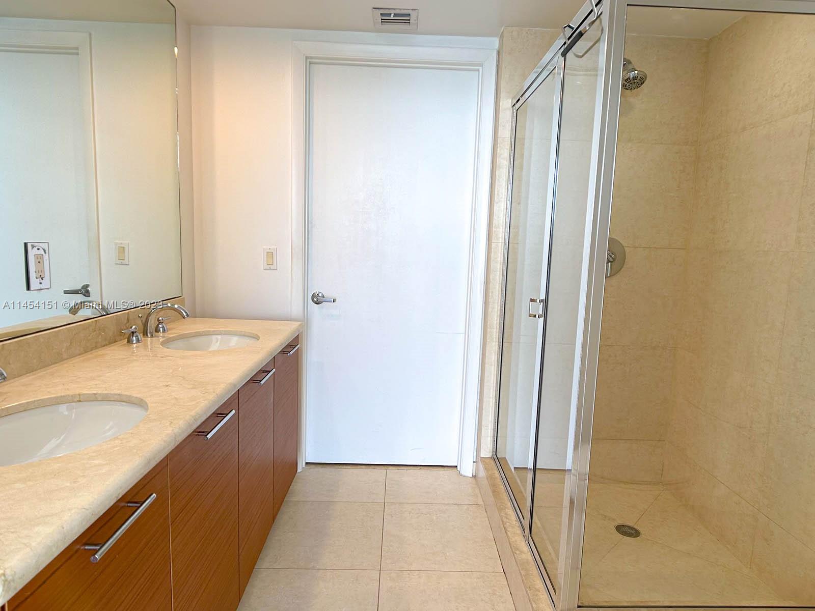 50 Biscayne Boulevard, Unit 3104 Miami, FL 33132 - Photo 31 of 52 a bathroom with a granite countertop sink and a mirror