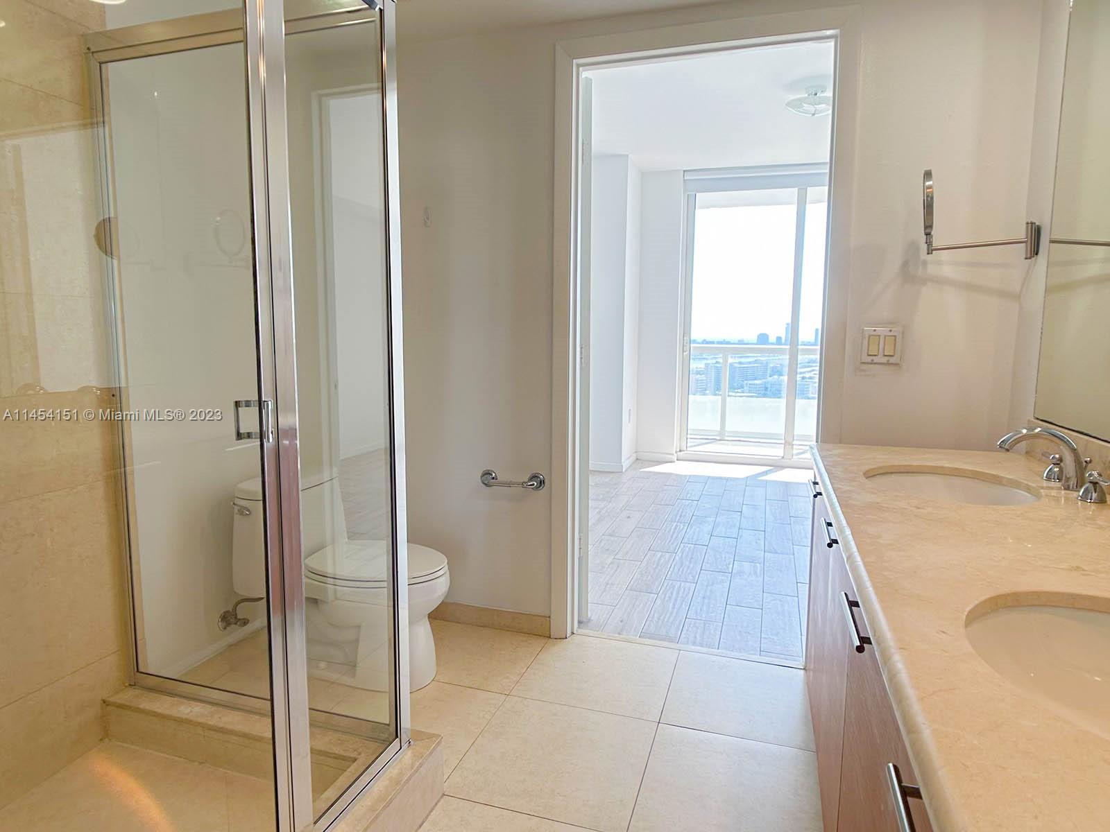 50 Biscayne Boulevard, Unit 3104 Miami, FL 33132 - Photo 33 of 52 a bathroom with a granite countertop sink a mirror and a bathtub