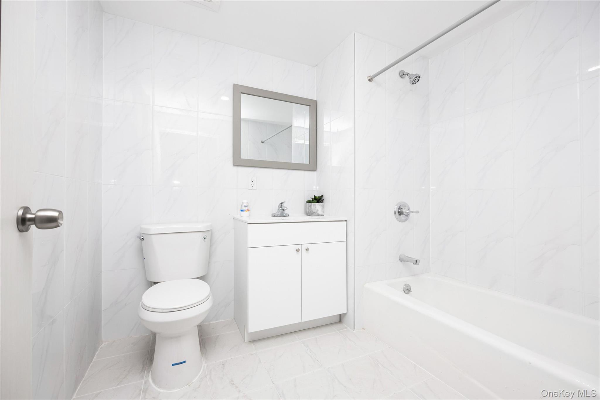 70-40 45th Avenue, Unit 2A Queens, NY 11377 - Photo 2 of 5 Bathroom featuring tile walls, shower combination, and vanity
