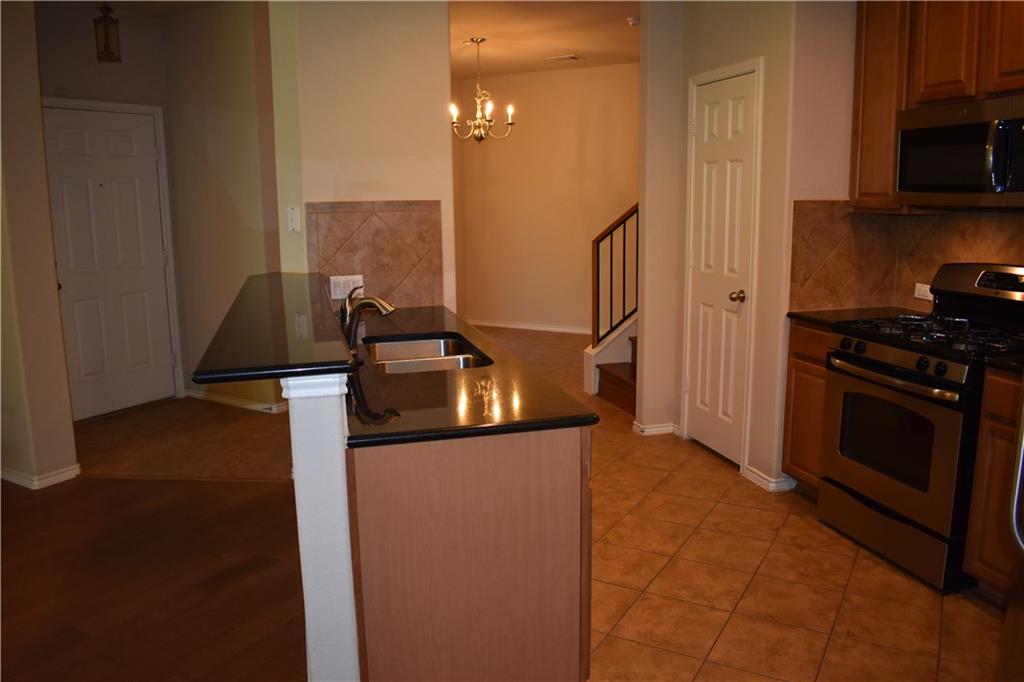 1310 West Parmer Lane, Unit 1503 Austin, TX 78727 - Photo 5 of 26 Kitchen featuring stainless steel appliances, a peninsula, a chandelier, wood finish cabinets, and light tile patterned flooring