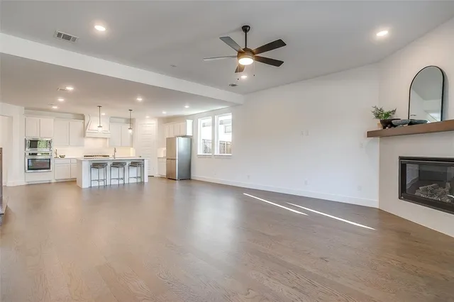 a view of a livingroom with a fireplace a ceiling fan and wooden floor
