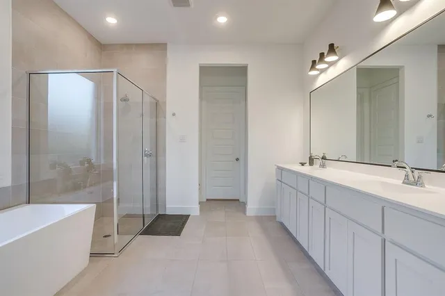 a bathroom with a double vanity sink a large mirror and a bathtub