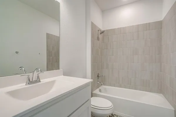 a bathroom with a granite countertop bathtub shower sink vanity mirror and toilet