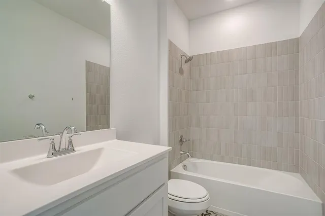 a bathroom with a granite countertop bathtub shower sink vanity mirror and toilet