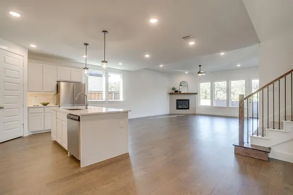 a kitchen with granite countertop a stove top oven a sink dishwasher and a fireplace with wooden floor