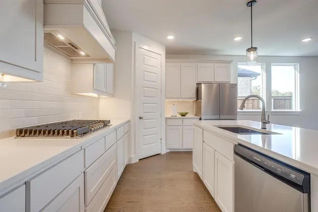 a kitchen with white cabinets and appliances