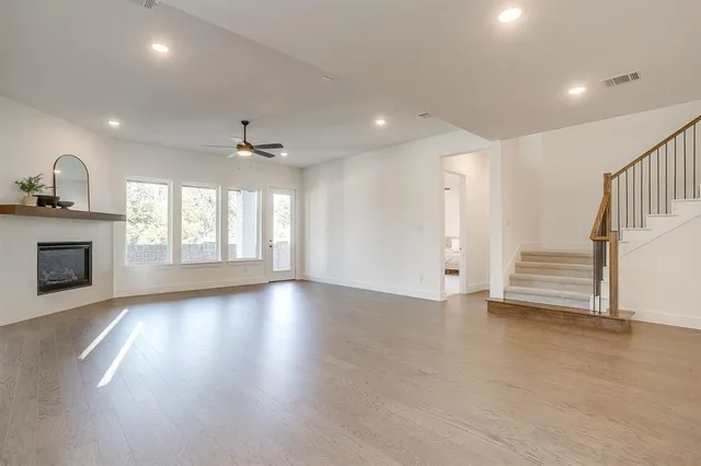 an empty room with wooden floor fireplace and windows