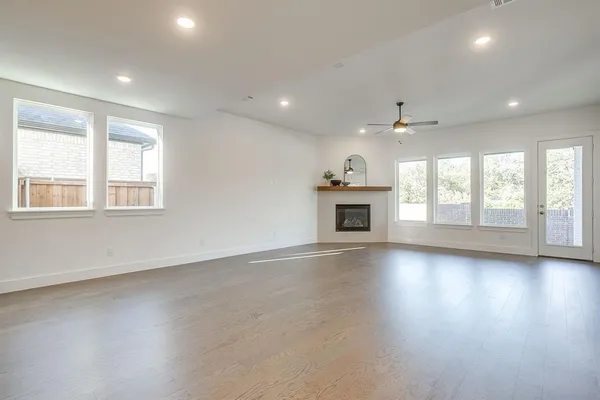 an empty room with wooden floor fireplace and windows