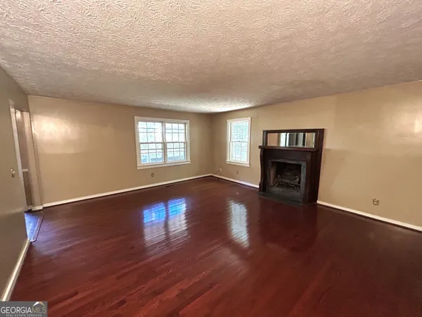 an empty room with wooden floor chandelier and windows