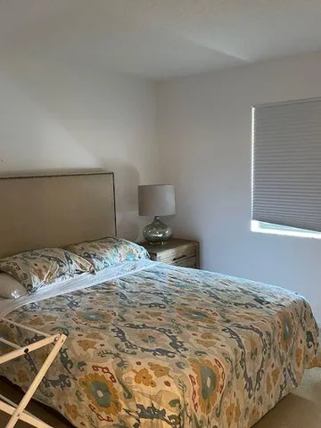 a bedroom with a bed and a lamp on dresser