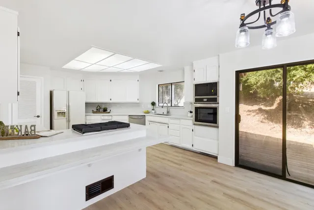 a kitchen with stainless steel appliances white cabinets a sink a stove a refrigerator and cabinets