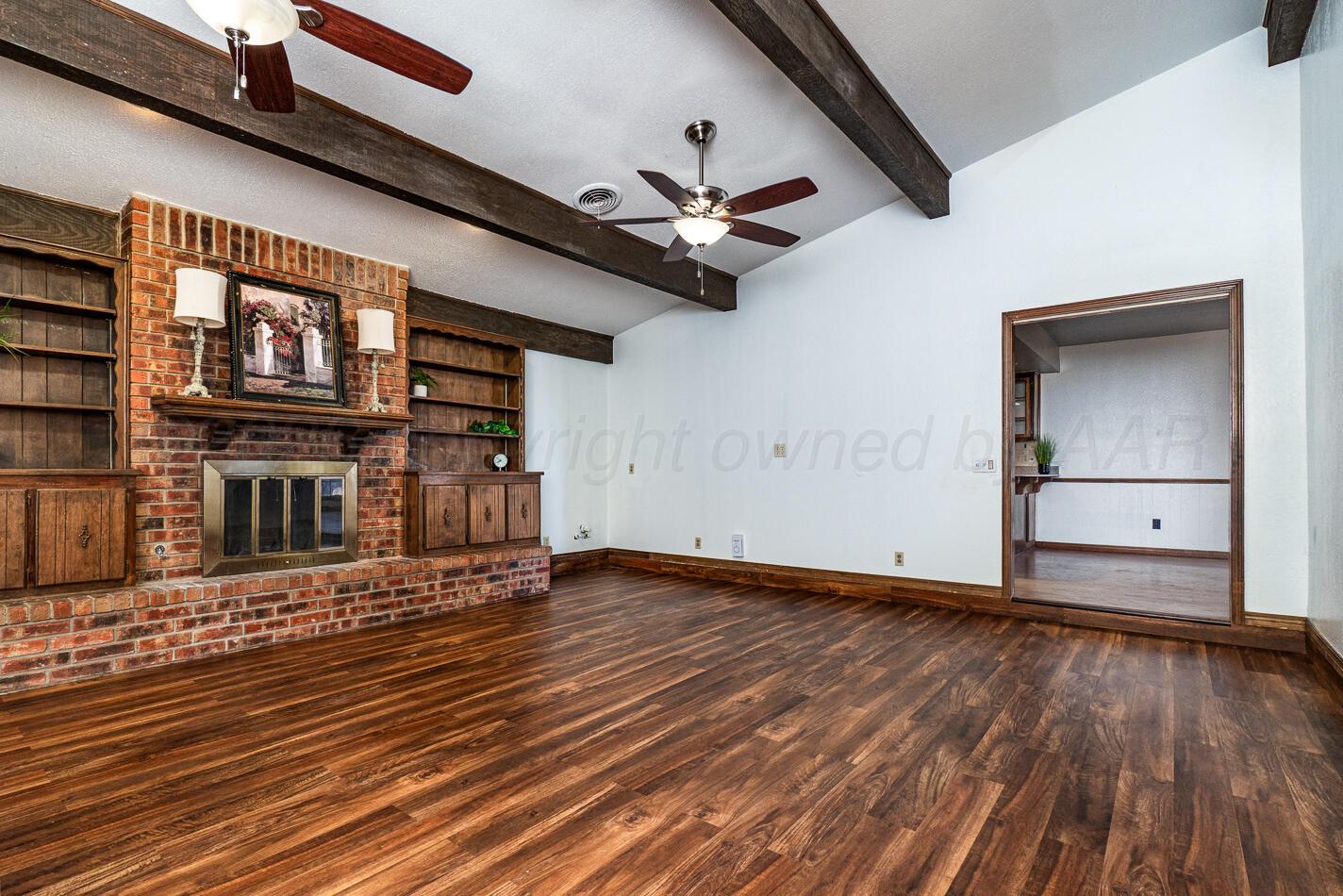 7803 Farrell Drive Amarillo, TX 79121 - Photo 3 of 29 an empty room with wooden floor chandelier fan and windows