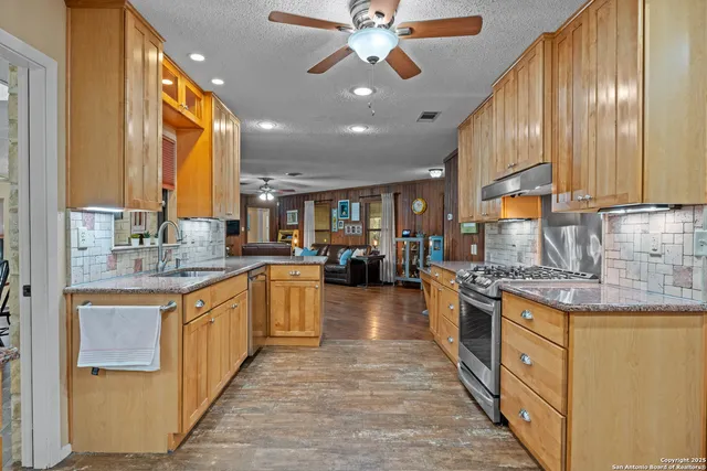 a large kitchen with stainless steel appliances granite countertop a large counter top a stove a sink and a refrigerator