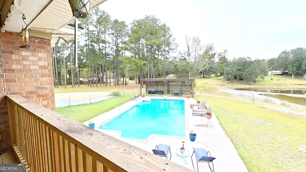 a view of a swimming pool with a patio and a yard