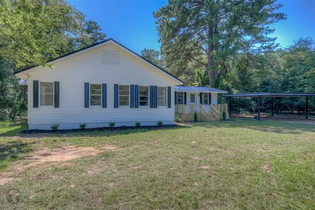 a view of a house with a yard and a large tree